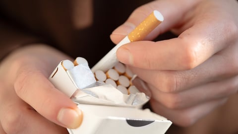 A man holds a pack of cigarettes in his hands, hand with a cigarette closeup. Person with a bad habit that is unhealthy; Shutterstock ID 2228396067