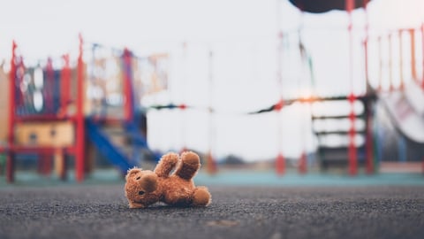 Lost teddy bear toy lying  on playground floor in gloomy day,Lonely and sad brown bear doll lied down alone in the park, Lost toy or Loneliness concept,International missing Children day; Shutterstock ID 2269475509