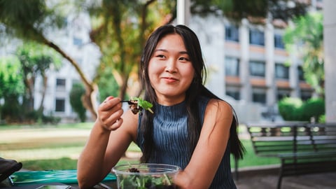 Smiling college student girl eating a healthy salad while taking a break with her friends; Shutterstock ID 2330249985