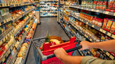 A man with a cart walks between store shelves and buys groceries. Large purchase at the supermarket.; Shutterstock ID 2447670445