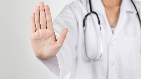 Asian female doctor give you reject gesture, hand close up with blurry background; Shutterstock ID 401536039