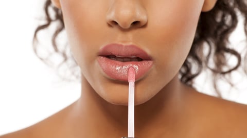 young beautiful black woman applied lipstick; Shutterstock ID 712950457