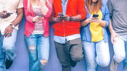 Teenagers texting mobile phone messages leaning on urban wall - Group of multiracial friends using cellular standing outdoors - Concept of students addiction to social network and telephone technology; Shutterstock ID 715081060
