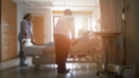 Doctor and nurse talking with patient lying in bed, Blurred hospital room image with sunset light effect between Doctor and Patient; Shutterstock ID 774940648