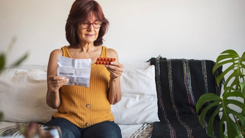 Une femme lit la monographie du médicament qu'elle s'apprête à prendre.