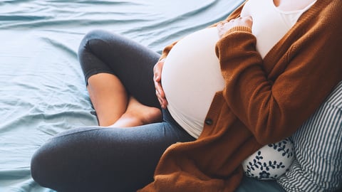 Une femme enceinte se repose dans un lit.