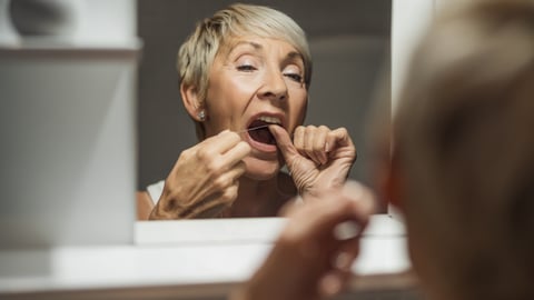 Une femme âgée se passe le fil dentaire 