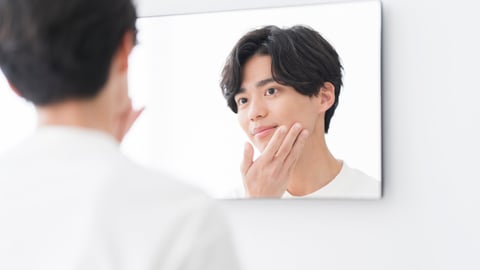 asian man looking at his reflection in the mirror