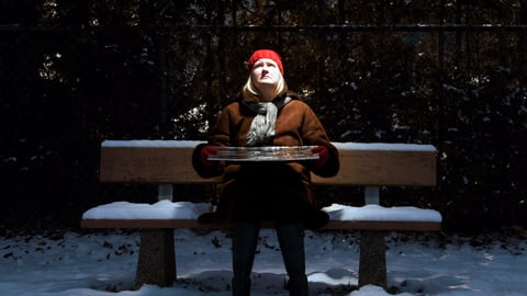 Une femme atteinte de dépression saisonnière est assise sur un banc dehors, en hiver.