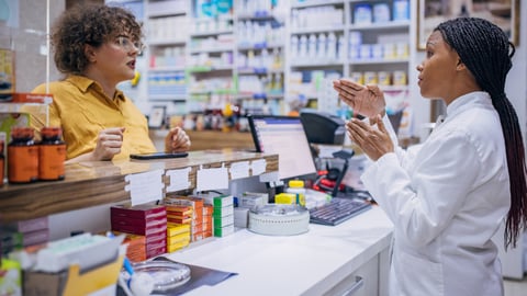 two dark skinned women having a conversation in pharmacy