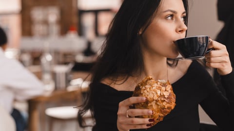 Photo of brunette teen woman ordering coffee and croissant. Young woman having breakfast with croissant and cup of coffee at the cafe. Girl drink mug of tea and hold croisant.; Shutterstock ID 2435005983