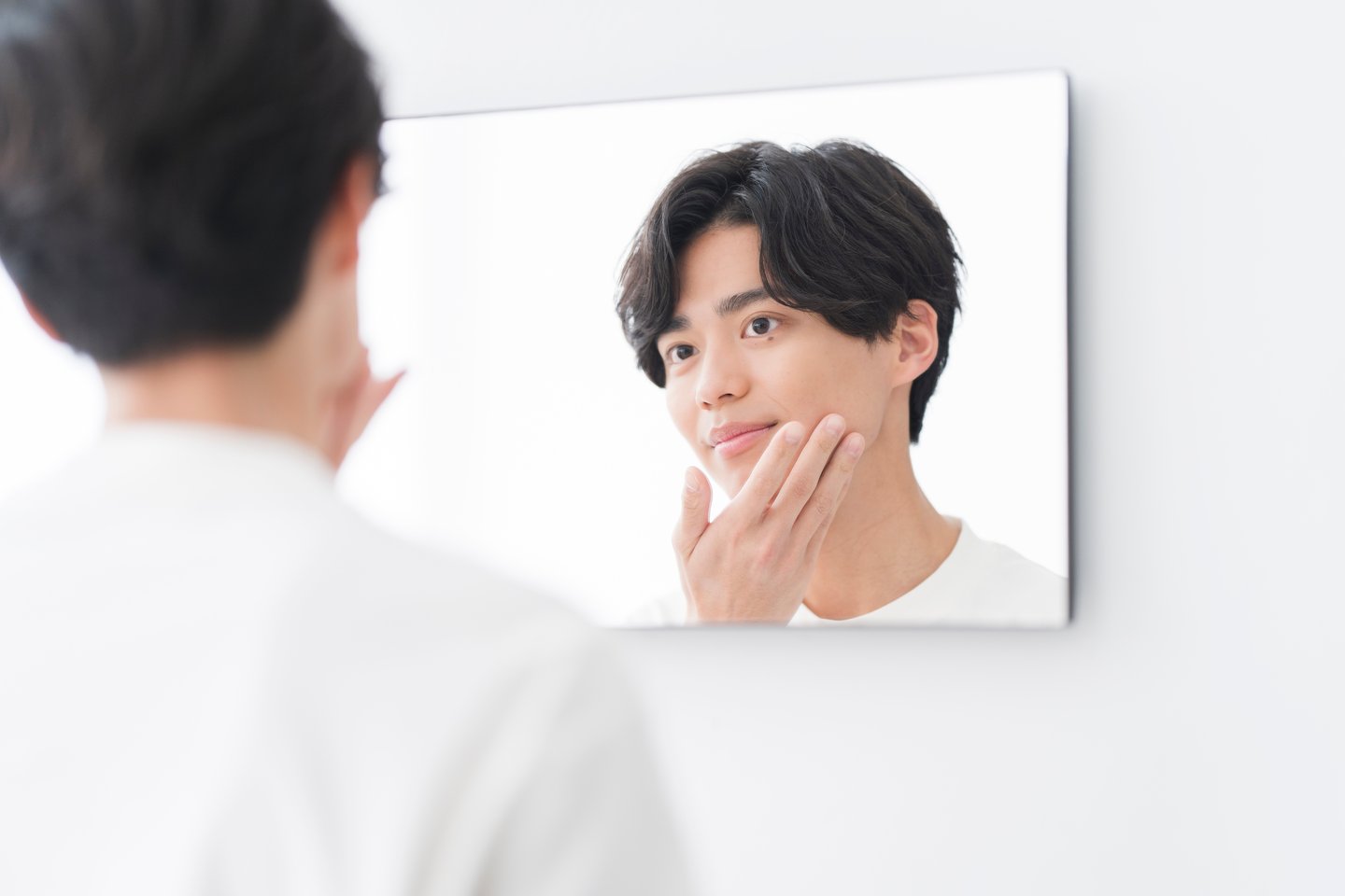 asian man looking at his reflection in the mirror