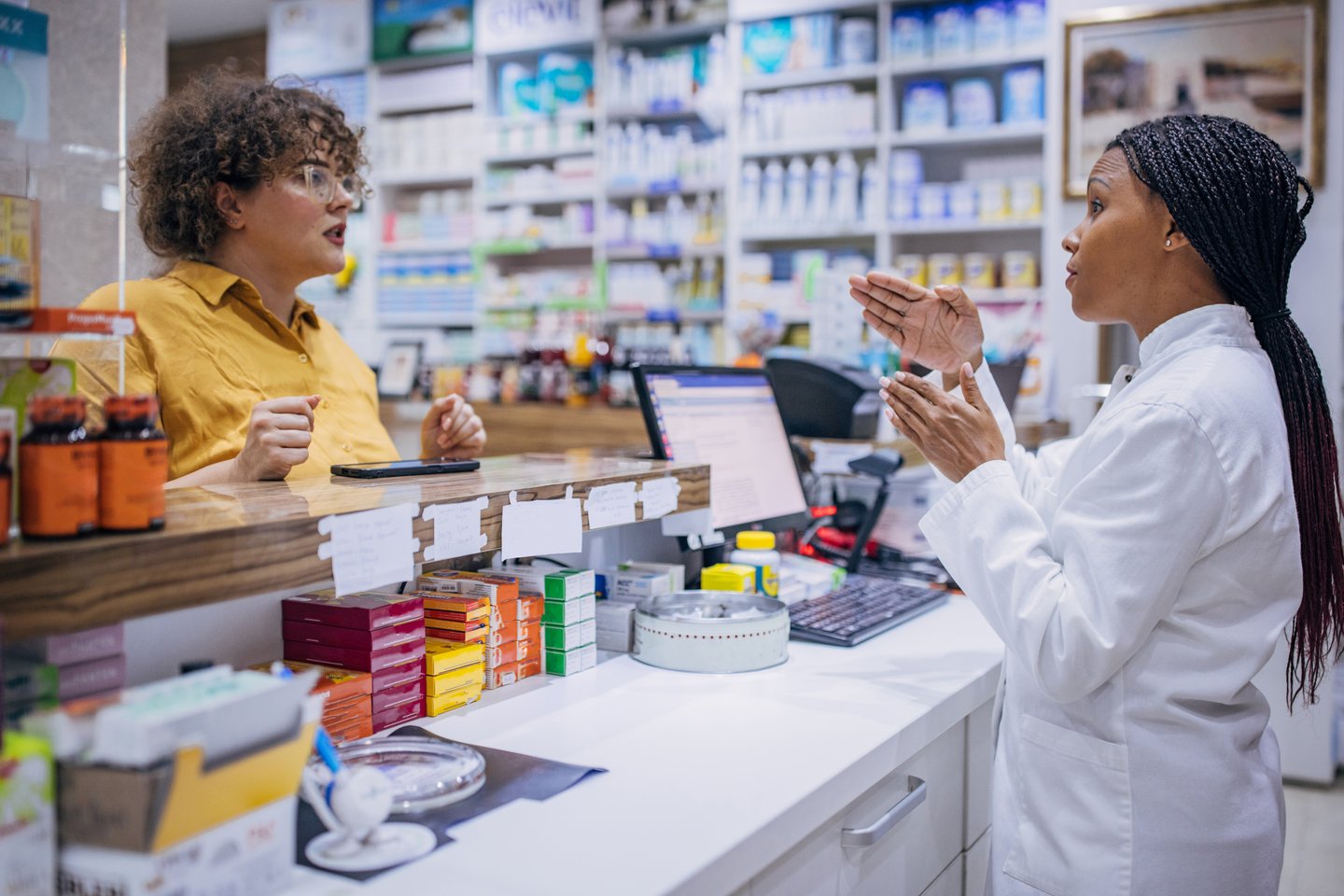 two dark skinned women having a conversation in pharmacy