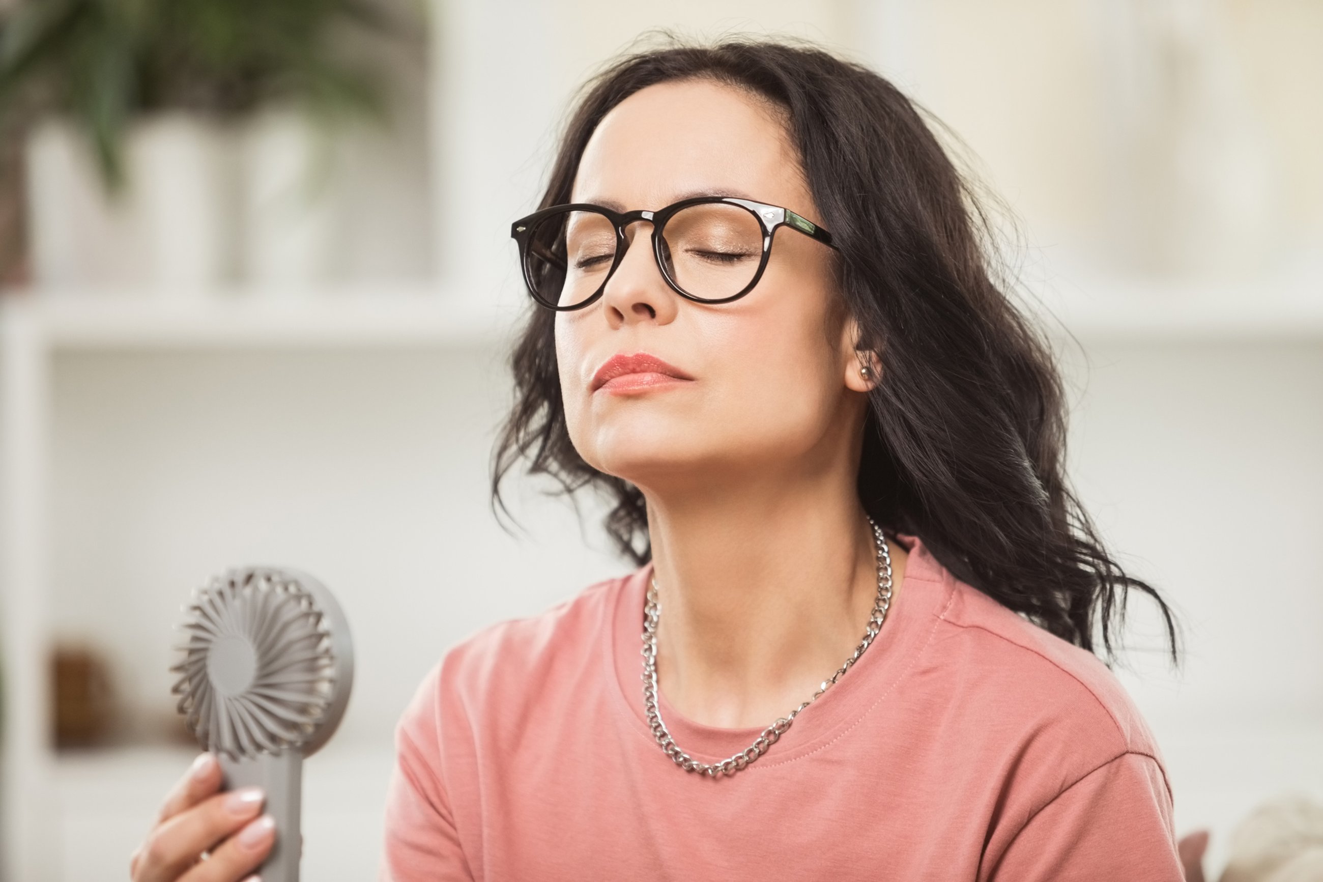 Woman cooling herself off with a fan